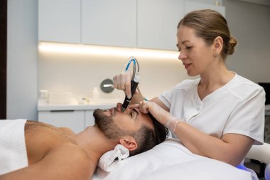 Şu anki terapi. Müşteriyle çalışan ve güncel terapiyi kullanan bir güzellik uzmanı.