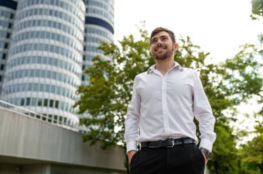 Keyfin yerinde. Koyu renk saçlı, beyaz gömlekli genç adam gülümsüyor.