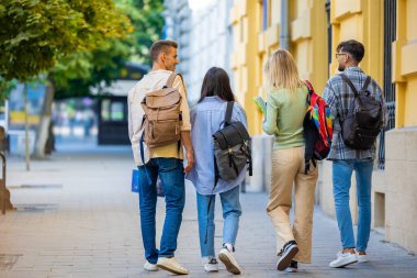 Sırt çantalı bir grup öğrenci derslerden sonra dışarıda vakit geçiriyorlar.