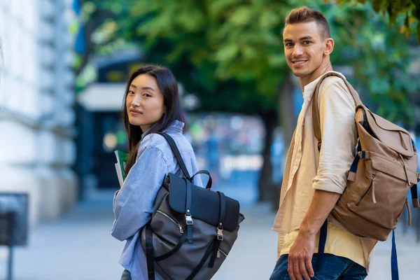 Two international students walking near the campus and smiling.