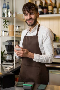 Pizzacının garsonu not alıyor ve gülümsüyor.