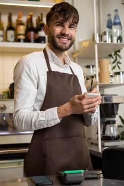 Pizzacının garsonu not alıyor ve gülümsüyor.