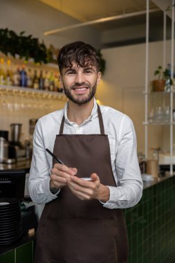 Önlüklü bir pizzacı sipariş hazırlığı için not alıyor.