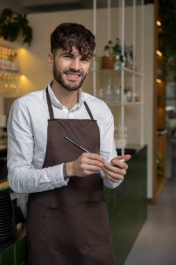 Önlüklü bir pizzacı sipariş hazırlığı için not alıyor.