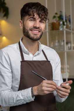 Önlüklü bir pizzacı sipariş hazırlığı için not alıyor.