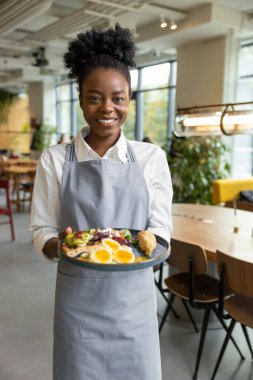 Önlüklü gülümseyen Afro-Amerikan garson.