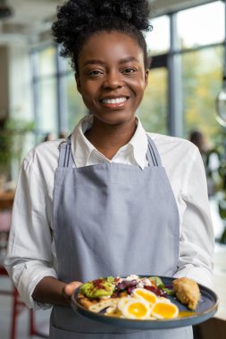 Önlüklü gülümseyen Afro-Amerikan garson.