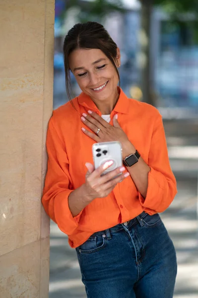 明るいオレンジ色のシャツでかわいい女性が興奮しています — ストック写真