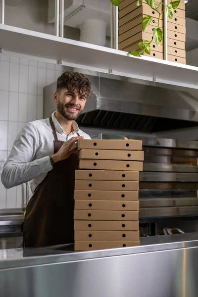 Male service man with many pizza boxes in pizzeria
