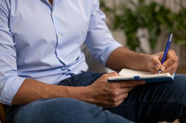 Evdeki kanepede oturan tanınmamış bir adam ve not defterine notlar yazıyor.