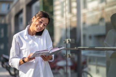 Güzel bir kadın telefonda konuşuyor ve ilgileniyor gibi görünüyor.
