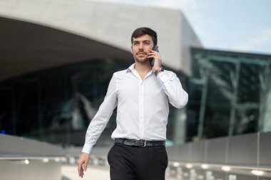 Telefon var. Koyu saçlı genç adam telefonda konuşuyor.