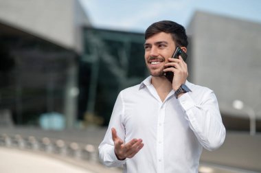 Telefon var. Koyu saçlı genç adam telefonda konuşuyor.