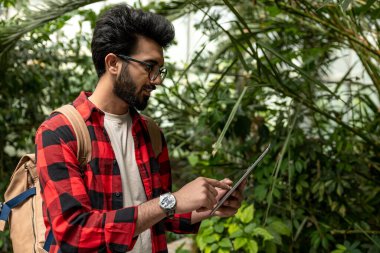 Botanik bahçesinde elinde tabletle Hintli bir adam