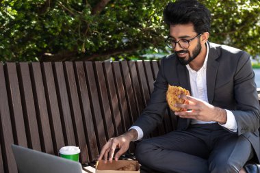 Hindu genç işadamı çalışıyor ve öğle yemeği yiyor.