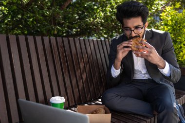 Hindu genç işadamı çalışıyor ve öğle yemeği yiyor.