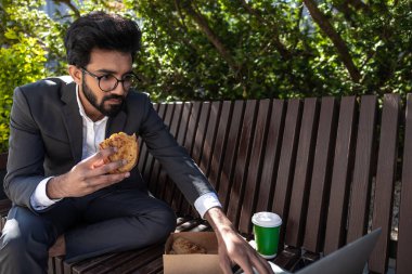 Hindu genç işadamı çalışıyor ve öğle yemeği yiyor.