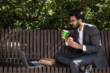 Hindu genç işadamı çalışıyor ve öğle yemeği yiyor.