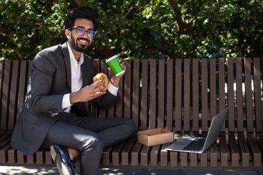 Hindu genç işadamı çalışıyor ve öğle yemeği yiyor.