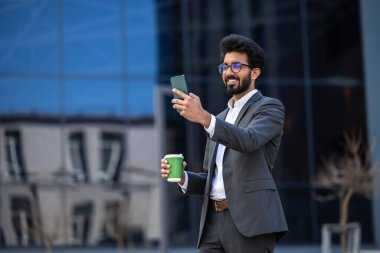 Elinde telefon olan zarif Hintli genç adam.