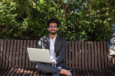 Genç işadamı bankta oturuyor ve çalışıyor.