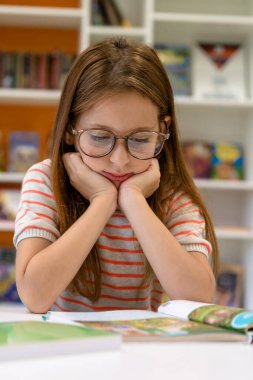 Sıkıcı kahverengi saçlı okul kütüphanesinde ders çalışmaya hazırlanıyor..