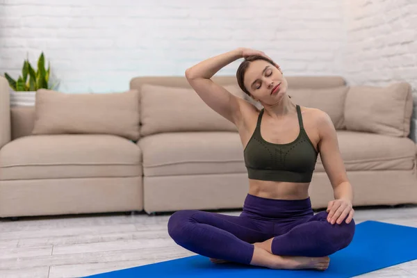 Body stretching. Young woman sitting in a lotus pose and doing stretching