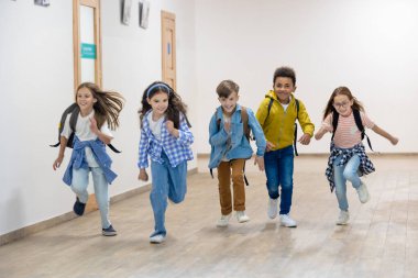 Tatilde okul koridorunda koşan bir grup ilkokul çocuğu..