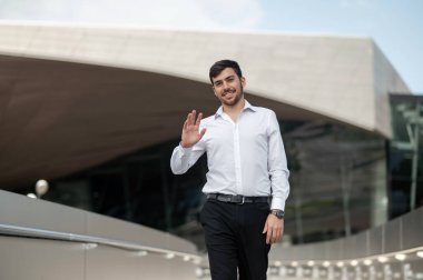 İş adamı. Beyaz gömlekli genç adam yürüyor ve gülümsüyor.