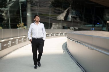 İş adamı. Beyaz gömlekli genç adam yürüyor ve gülümsüyor.