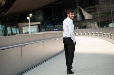 İş adamı. Beyaz gömlekli genç adam yürüyor ve gülümsüyor.