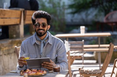 Pizzacı. Pizzacıda pizza yiyen genç Hintli adam.