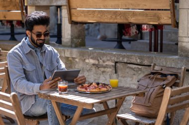Öğle yemeği vakti. Hindu genç adam pizzacıda öğle yemeği yiyor.