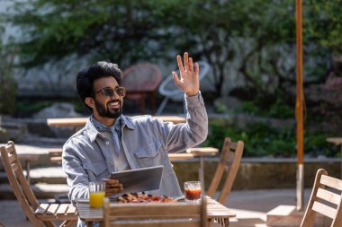 Öğle yemeği vakti. Hindu genç adam pizzacıda öğle yemeği yiyor.