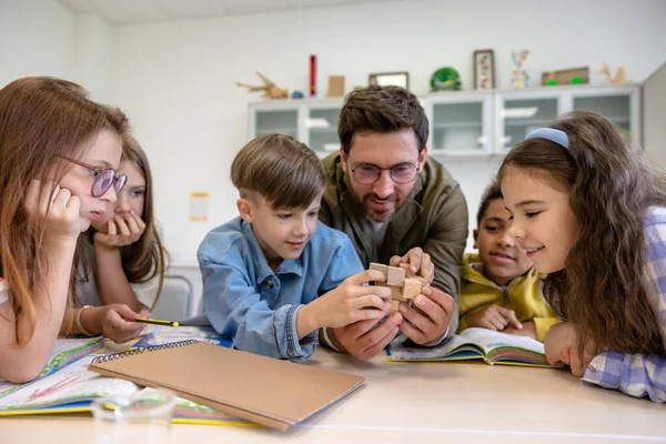 Erkek öğretmen ve çocuklar birlikte yeni bir kimya dersi öğreniyorlar..
