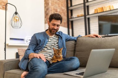 Evde çalışan genç bir adam, kedisi evde yatıyordu.