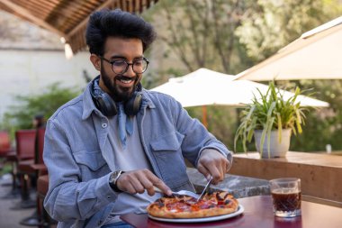 Pizzacı. Kafede masada oturan bir adam pizza kesiyor.