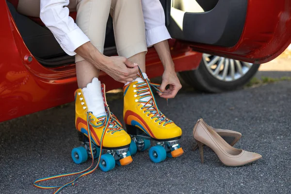 Unrecognizable unknown woman sitting in car preparing for roller skate ride
