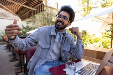 Bir kafede. Genç Hintli adam kafede garsonu bekliyor.