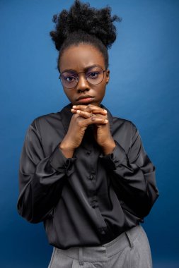 Siyah gömlekli, koyu tenli genç kadın ciddi görünüyor.