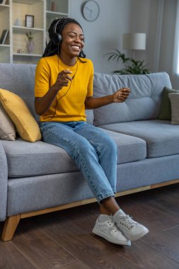 Şirin, genç, Afro-Amerikan bir kadın müzik dinliyor ve mutlu görünüyor.