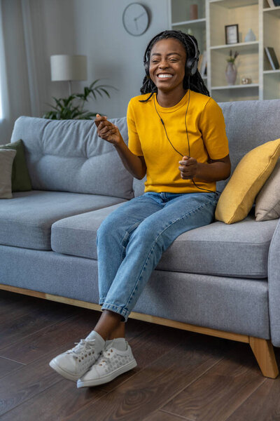 Милая молодая африканская американка слушает музыку и выглядит счастливой.