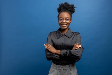 Siyah ipeksi gömlekli, kendinden emin, koyu tenli genç bir kadın.