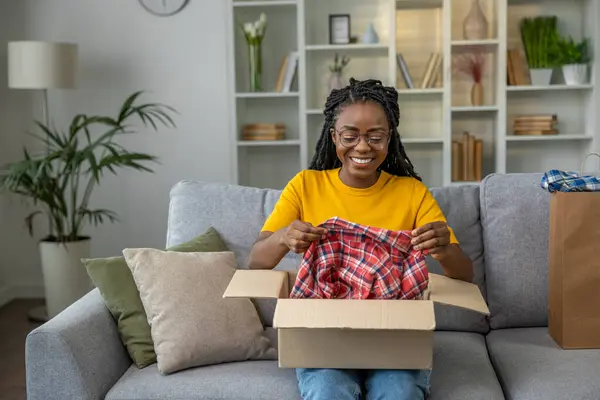 Smiling young woman opening a box with clothes