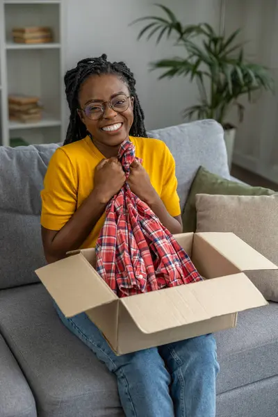 Smiling Dark Skinned Woman Opening Box Clothes Looking Contented — Stock Photo, Image