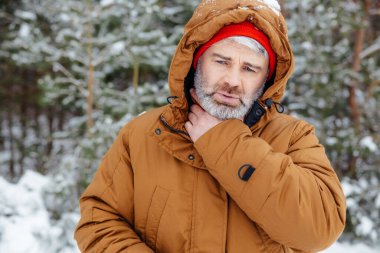 Kötü hissediyorum. Kış ormanındaki adam hasta ve hasta görünüyor.