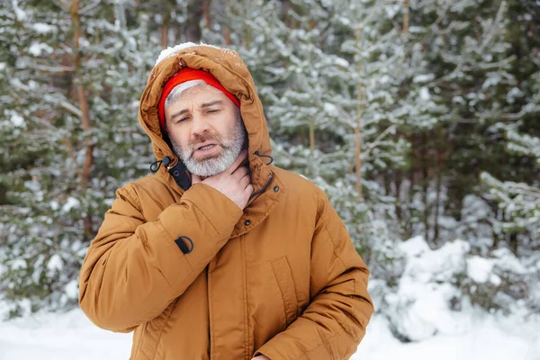 Feeling bad. Man in a winter forest looking sick and unwell