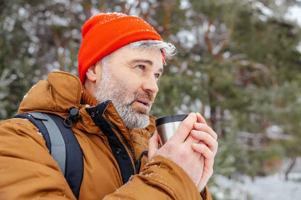 Getting warm. Man with thermos in hands in a snowy forest