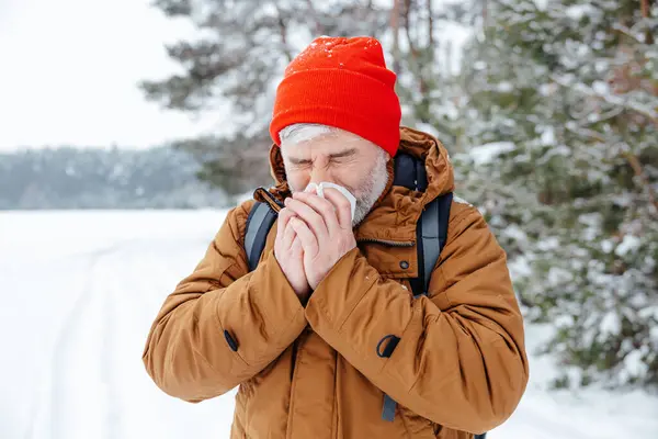 Got sick. Man in a winter forest looking sick and got running nose