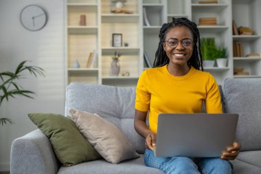 Gözlüklü gülümseyen genç kadın evde çalışıyor.